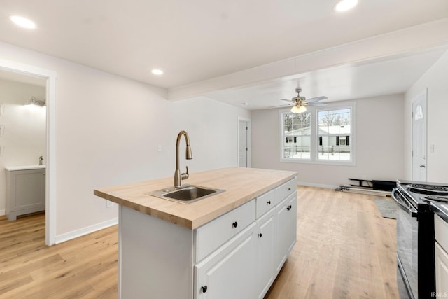 kitchen featuring sink, black electric range, white cabinets, and butcher block countertops