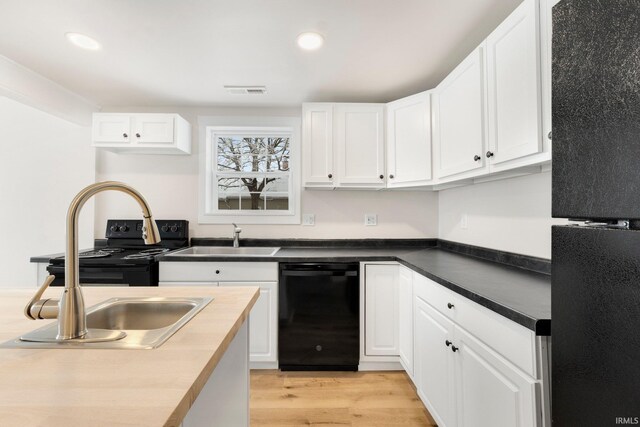 kitchen featuring white cabinetry, sink, butcher block countertops, and black appliances