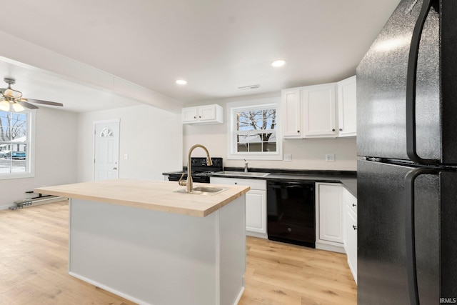 kitchen featuring white cabinetry, butcher block countertops, a kitchen island, and black appliances