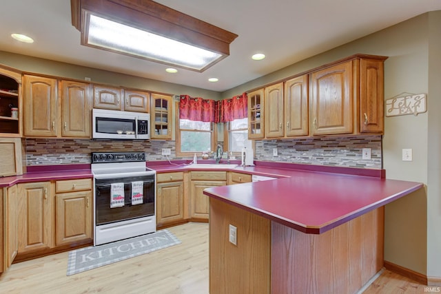 kitchen featuring backsplash, white appliances, kitchen peninsula, and light hardwood / wood-style flooring