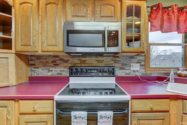 kitchen featuring range with electric stovetop, tasteful backsplash, and sink