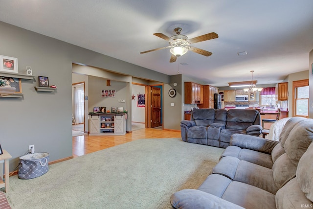 carpeted living room featuring ceiling fan with notable chandelier