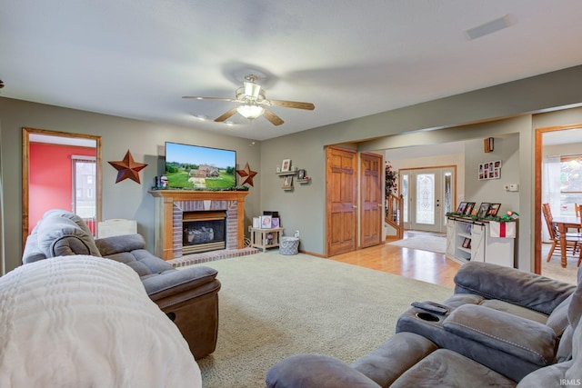 carpeted living room featuring ceiling fan, a fireplace, and a healthy amount of sunlight