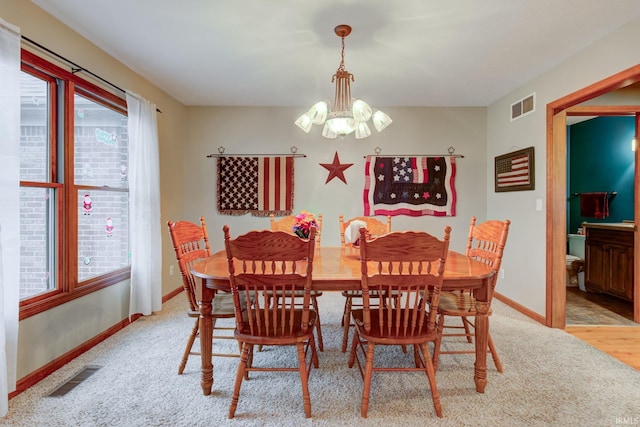 carpeted dining area with an inviting chandelier