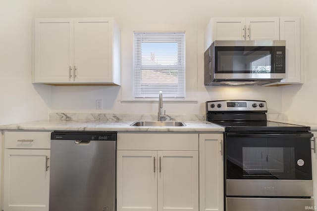 kitchen with white cabinetry, sink, light stone countertops, and appliances with stainless steel finishes