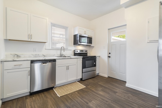 kitchen with appliances with stainless steel finishes, dark hardwood / wood-style flooring, white cabinetry, and sink