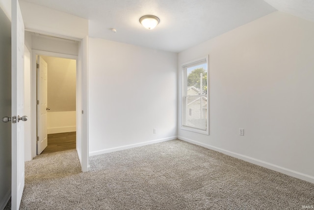 carpeted spare room with lofted ceiling