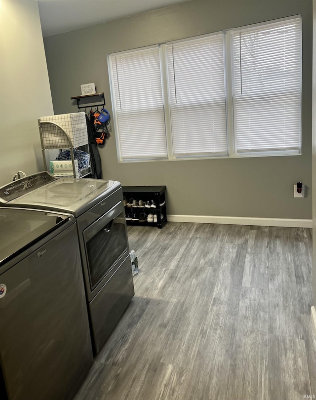 clothes washing area with washer and clothes dryer, light hardwood / wood-style floors, and cabinets