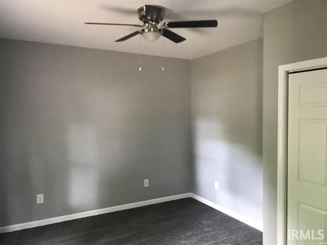 spare room featuring ceiling fan and dark carpet