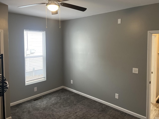 spare room featuring dark carpet and ceiling fan