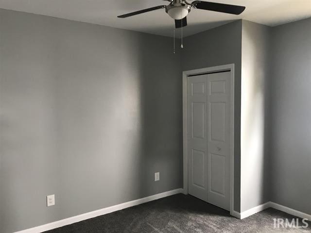 unfurnished bedroom featuring dark colored carpet, ceiling fan, and a closet