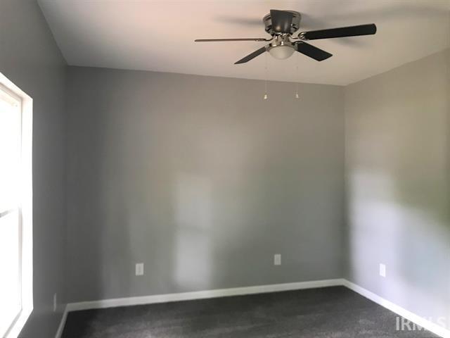 empty room with dark colored carpet and ceiling fan