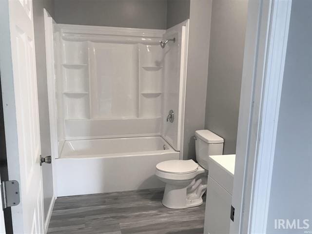 full bathroom with hardwood / wood-style floors, vanity, shower / bathtub combination, and toilet