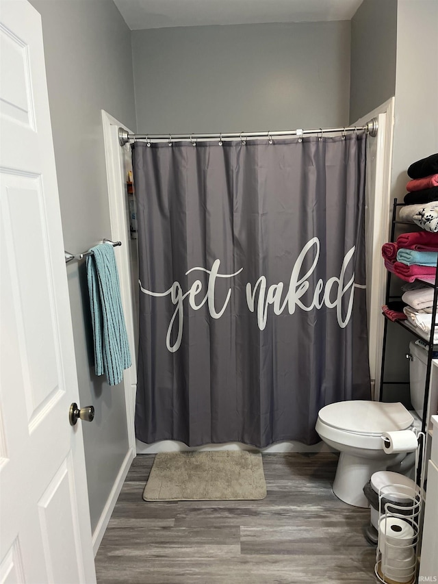 bathroom with hardwood / wood-style floors, toilet, and walk in shower