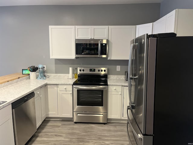 kitchen with light wood-type flooring, white cabinetry, and appliances with stainless steel finishes