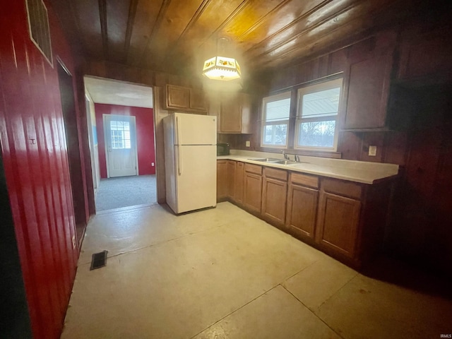 kitchen featuring pendant lighting, white refrigerator, wooden ceiling, and sink