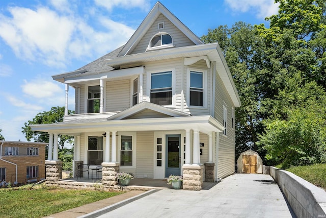 view of front of property featuring covered porch and a storage shed