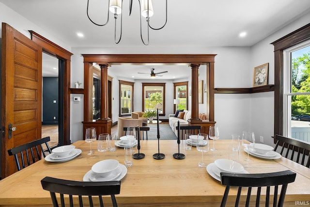 dining space with decorative columns and ceiling fan with notable chandelier