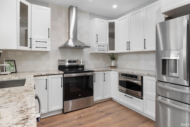 kitchen with white cabinets, appliances with stainless steel finishes, tasteful backsplash, and wall chimney exhaust hood