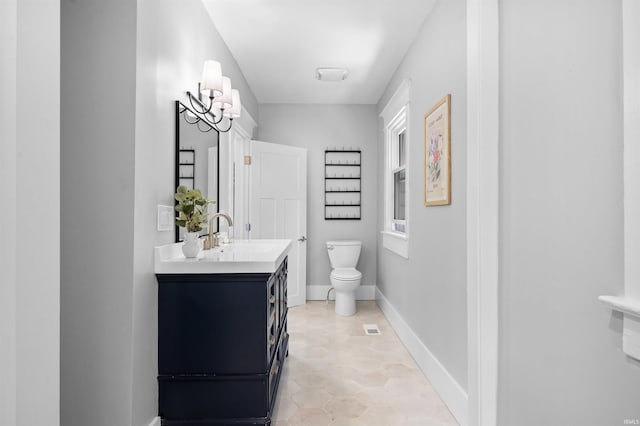 bathroom with a wealth of natural light, vanity, a notable chandelier, and toilet