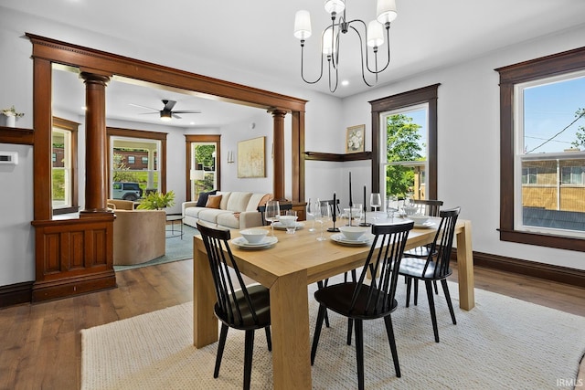 dining area with ceiling fan with notable chandelier, wood-type flooring, a wealth of natural light, and decorative columns