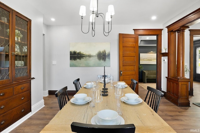 dining room featuring dark hardwood / wood-style flooring, ornate columns, and an inviting chandelier