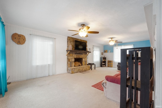 carpeted living room with a fireplace, ceiling fan, and wood walls