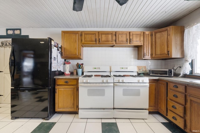 kitchen featuring tasteful backsplash, black fridge, and white range with gas stovetop