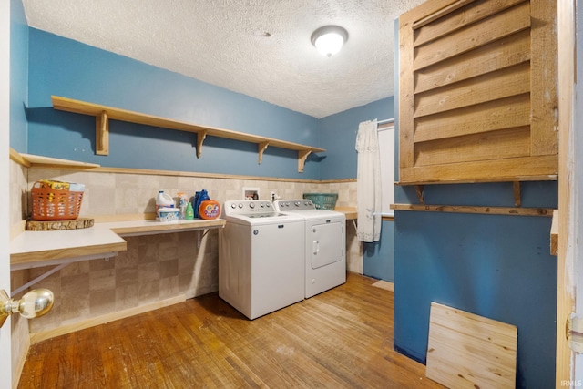 laundry area featuring a textured ceiling, light hardwood / wood-style floors, and washer and clothes dryer