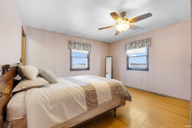 bedroom with multiple windows, light hardwood / wood-style flooring, and ceiling fan