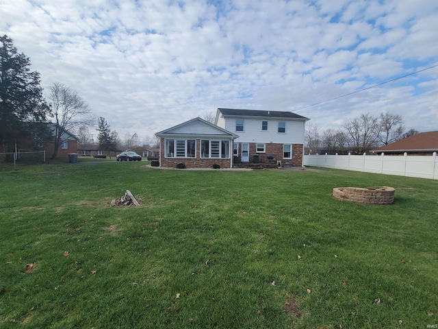 rear view of property with a fire pit and a lawn