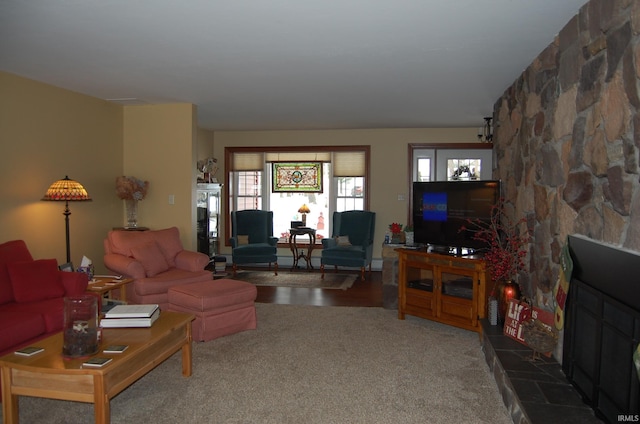 carpeted living room with a stone fireplace