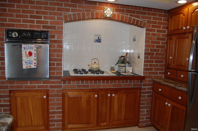 kitchen featuring wall oven, stainless steel refrigerator, dark stone counters, and white gas stovetop