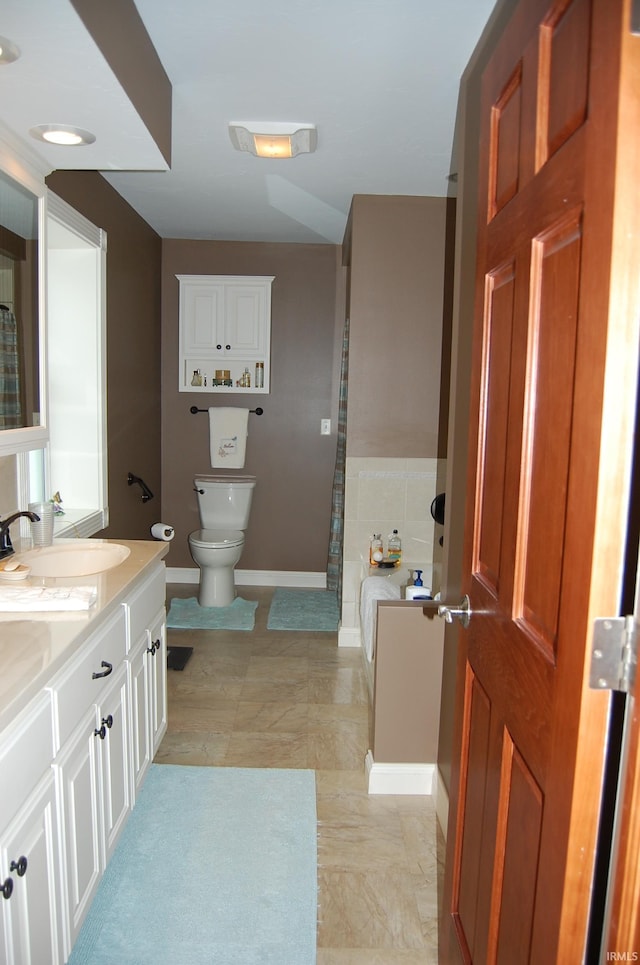 bathroom featuring tile patterned floors, vanity, toilet, and a bath