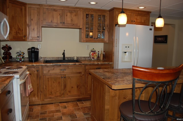 kitchen featuring a drop ceiling, white appliances, sink, pendant lighting, and dark stone countertops