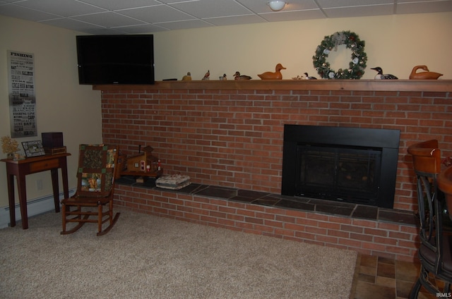 interior space with baseboard heating, a fireplace, carpet floors, and a drop ceiling