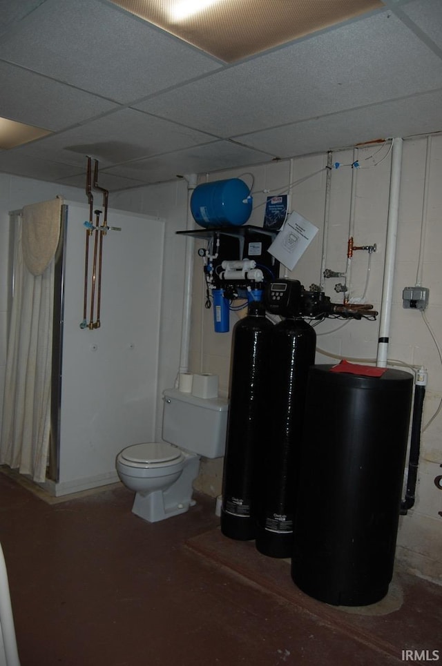 interior space with concrete flooring, toilet, and a drop ceiling