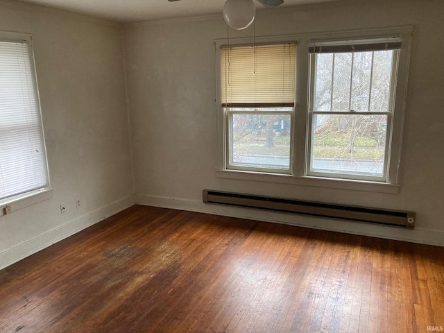 empty room featuring dark hardwood / wood-style floors, a healthy amount of sunlight, ceiling fan, and a baseboard radiator