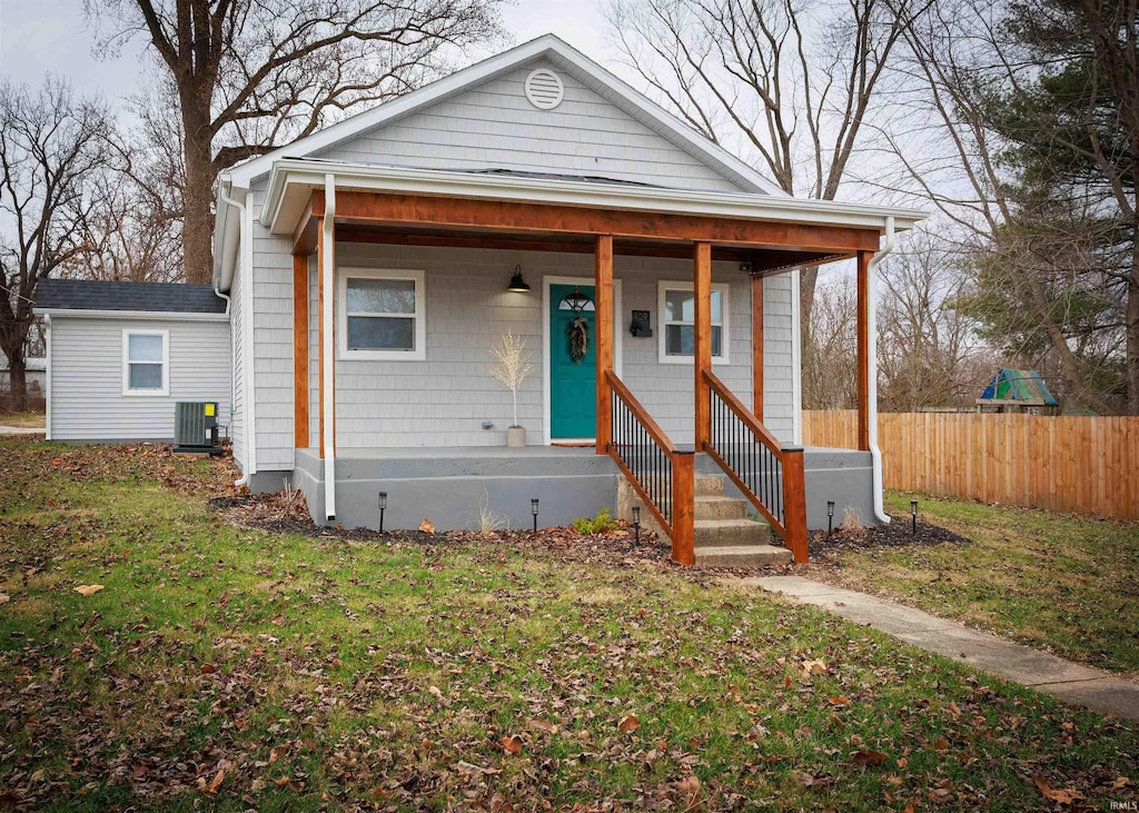 bungalow featuring covered porch, a front lawn, and central AC unit