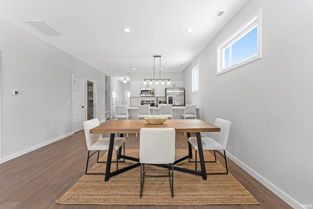 dining space with baseboards, visible vents, and dark wood finished floors