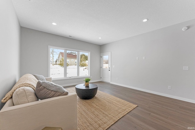 living room with a textured ceiling, baseboards, dark wood-type flooring, and recessed lighting