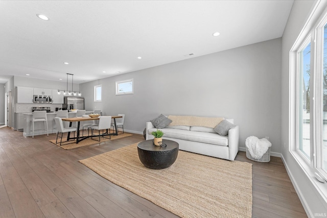 living area featuring light wood finished floors, recessed lighting, and baseboards