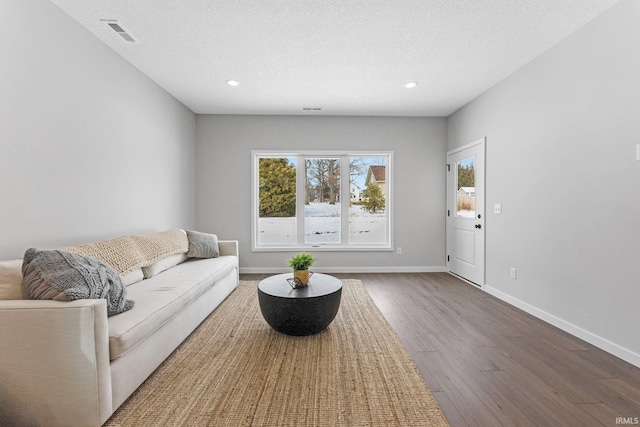 living area with recessed lighting, visible vents, a textured ceiling, wood finished floors, and baseboards