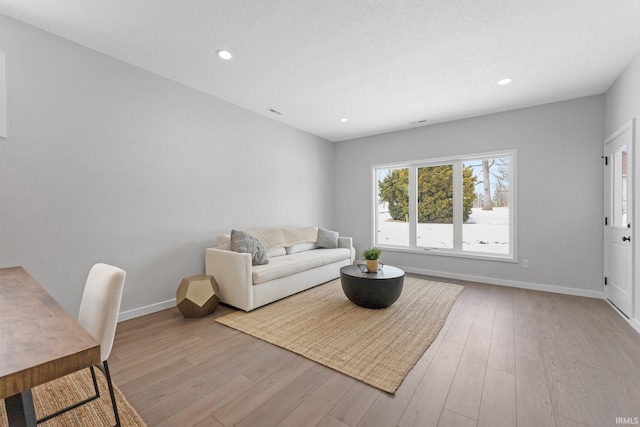 living room with light wood finished floors, visible vents, baseboards, a textured ceiling, and recessed lighting