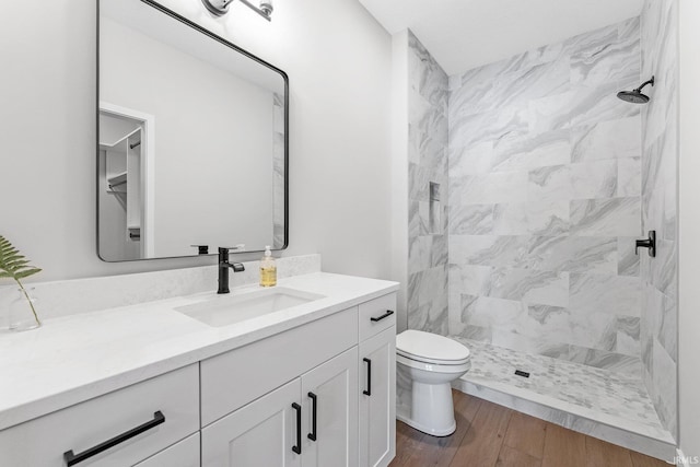 bathroom with toilet, vanity, a shower stall, and wood finished floors