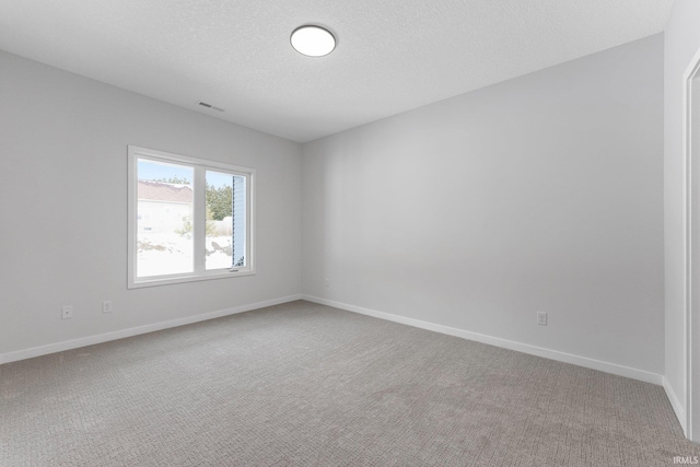 spare room featuring carpet floors, baseboards, visible vents, and a textured ceiling