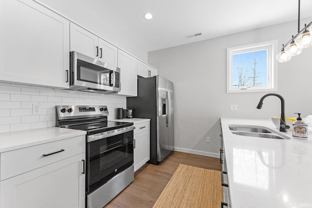 kitchen with stainless steel appliances, white cabinetry, a sink, and visible vents