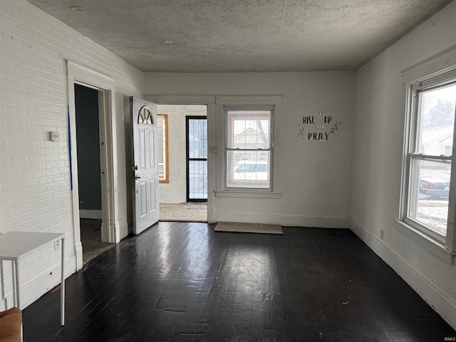 unfurnished room with a textured ceiling, dark hardwood / wood-style floors, and plenty of natural light