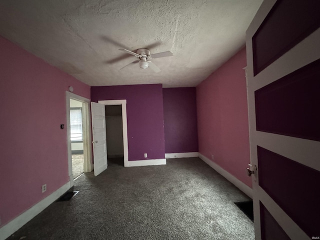 unfurnished bedroom with ceiling fan, dark carpet, and a textured ceiling