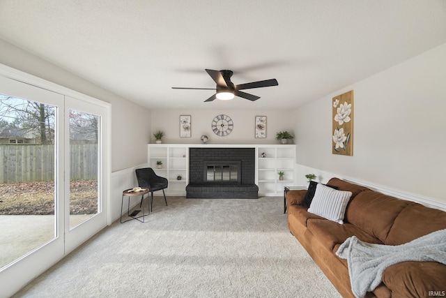 carpeted living room with ceiling fan, plenty of natural light, and a brick fireplace